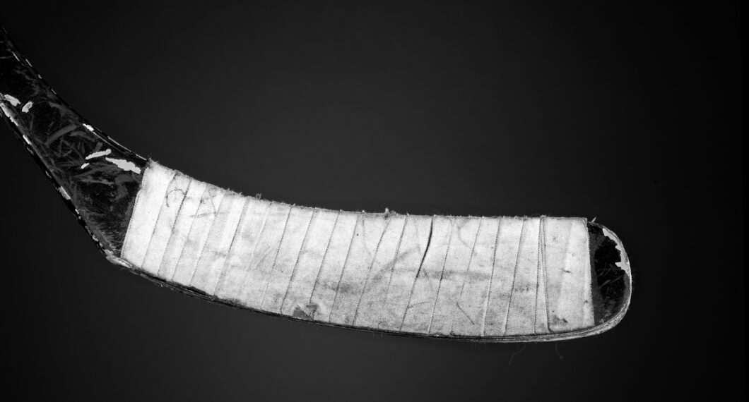 A taped and used hockey stick on a gradient backdrop.