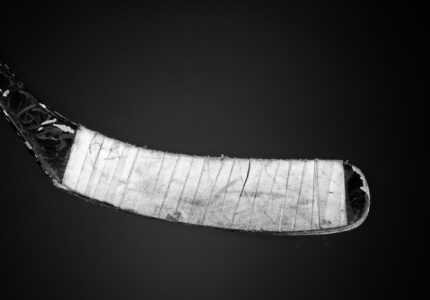 A taped and used hockey stick on a gradient backdrop.