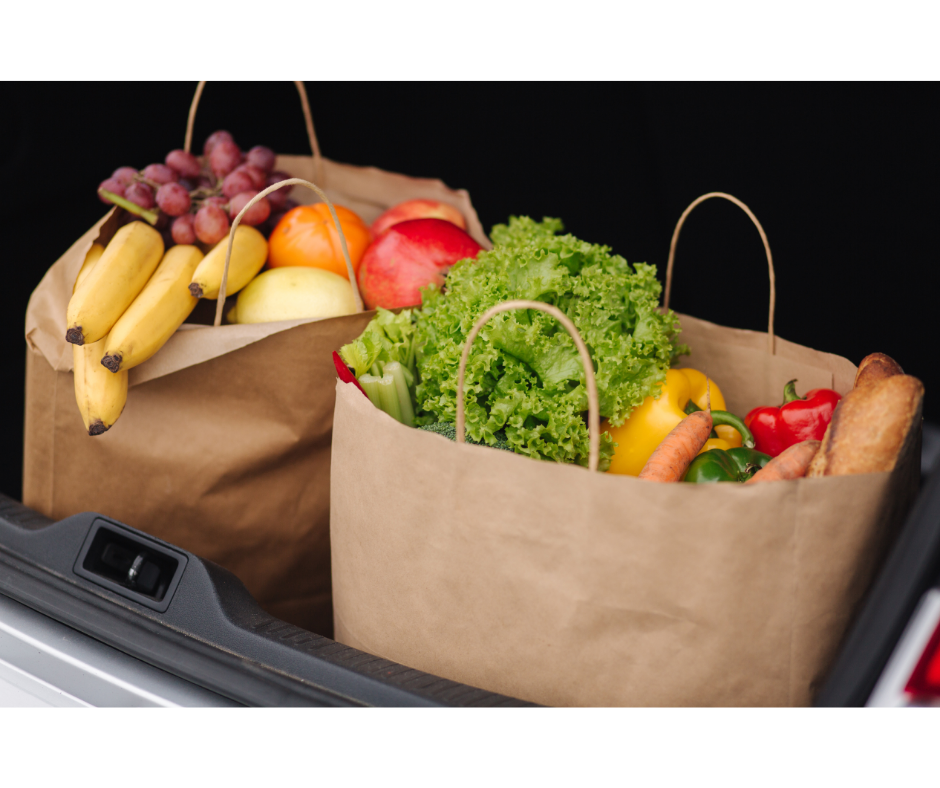 grocery bags filled with produce inside the trunk of a car