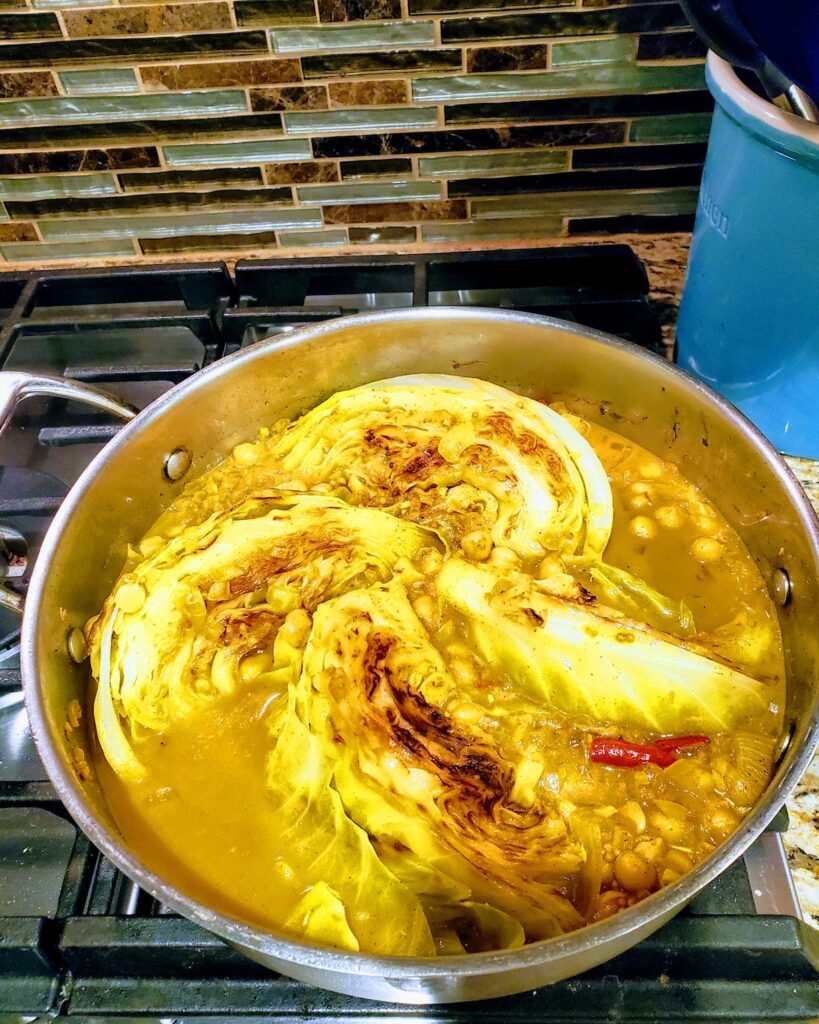 Cabbage with chickpeas in skillet, topped with chiles. A spicy, warm vegetarian/vegan holiday recipe.