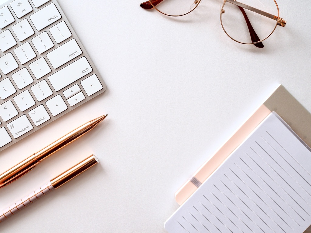 Glasses, notebook and laptop on desk