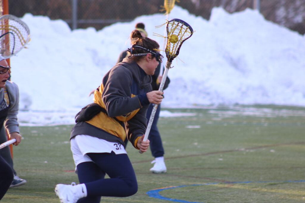 Womens lacrosse player showing a lacrosse stick. 