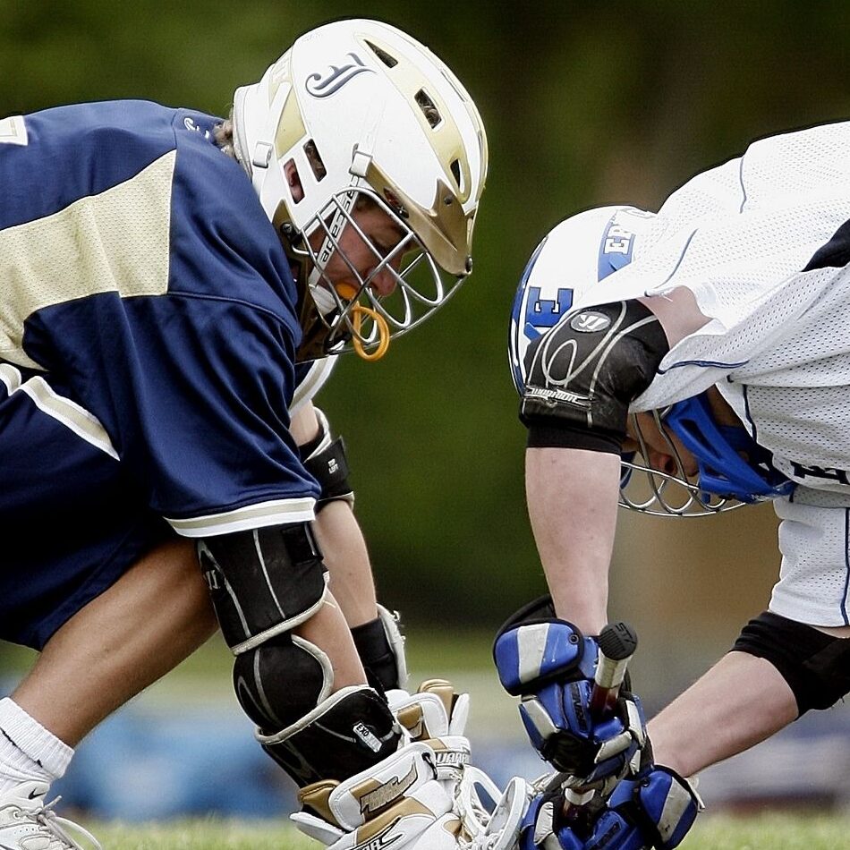 A photo of two men's lacrosse players doing the Face-Off.