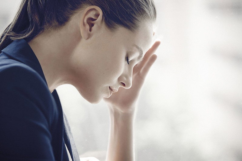 A stressed women holds a hand to her forehead.