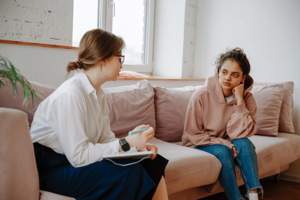 Two women sitting on a couch talking about their stress