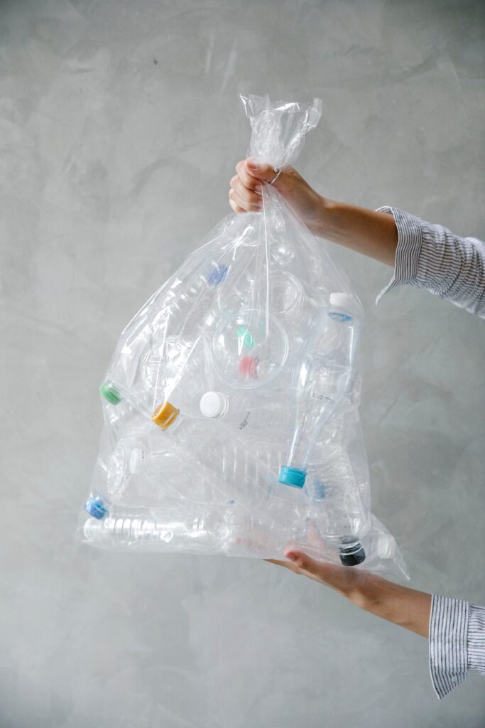 sustainable business clear plastic bag of plastic bottles held up by two hands