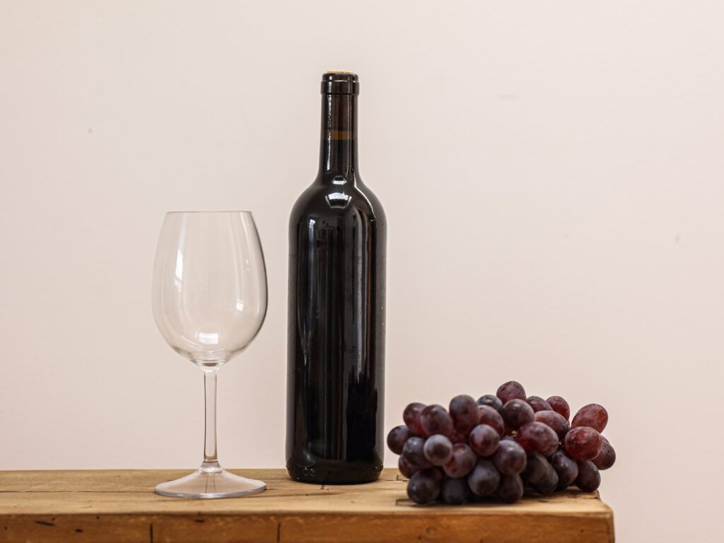wine glass, wine bottle, and grapes on wooden table; symbolizes sustainable business practice