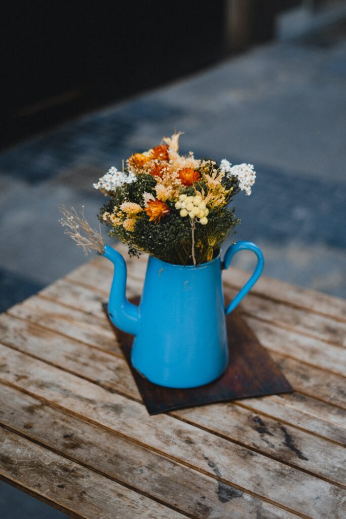 sustainable living upcycled blue ceramic teapot with flowers on top of wood table
