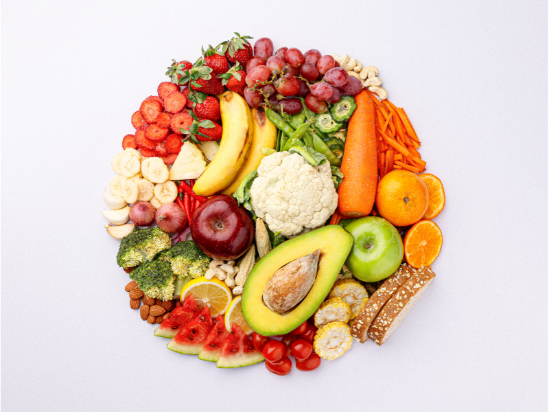brightly colored fresh fruits and vegetables arranged in a circle on white background