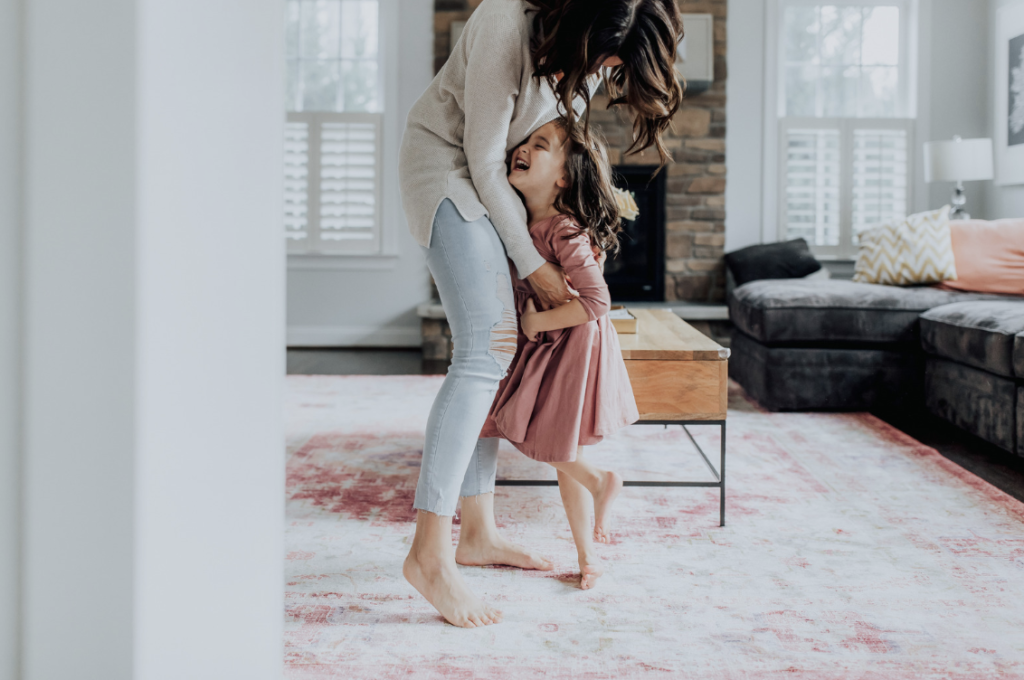mother and daughter dancing in living room