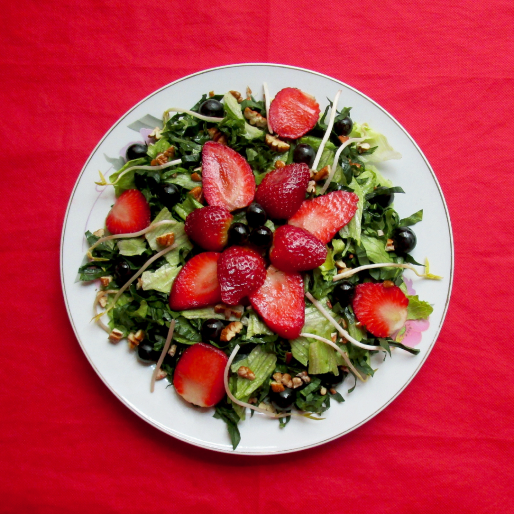 strawberries on a bed of spinach in a bowl with red background