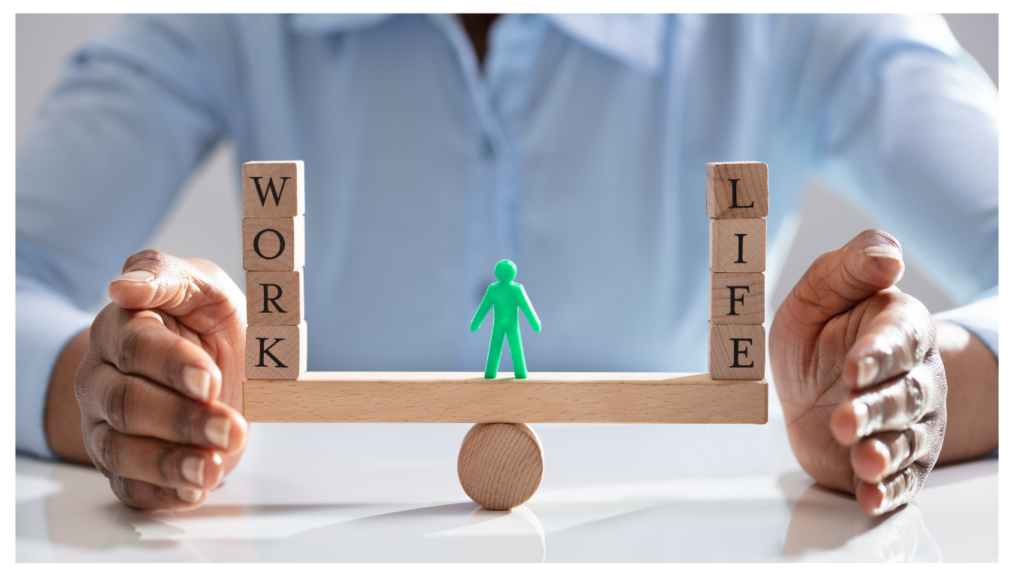 Two hands apart with blocks in the middle stacked on the left to say work and stacked on the right to say life. A green figure is in the middle balancing on a wood plank.