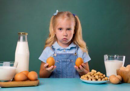 child living with food allergies frowning at eggs, milk, peanuts