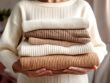 Arms holding a pile of folded clothes