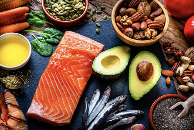 A photo of healthy foods, such as salmon, nuts, avocado and carrots.