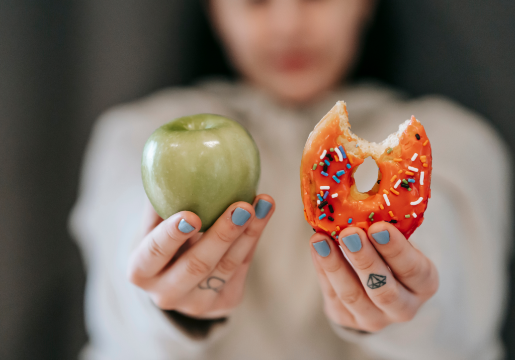 a woman holding a donut and an apple